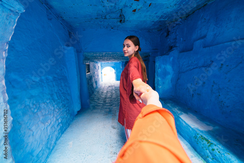 in frame the hand holding the hand of a girl going deeper into the corridor in the blue city of morocco © nelen.ru
