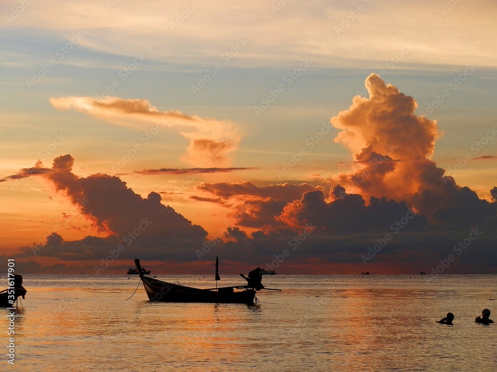 Sunset with majestic cloudscape and boat lying moored on the beach of Koh Tao, Thailand