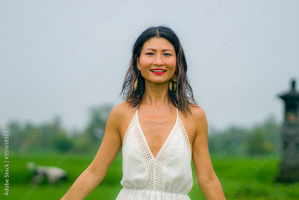 outdoors holidays portrait of attractive and happy middle aged Asian Chinese woman in white dress enjoying freedom and nature at green field landscape carefree and cheerful outdoors holidays portrait of attractive and happy middle aged Asian Chinese woman in white dress enjoying freedom and nature at green field landscape carefree and cheerful