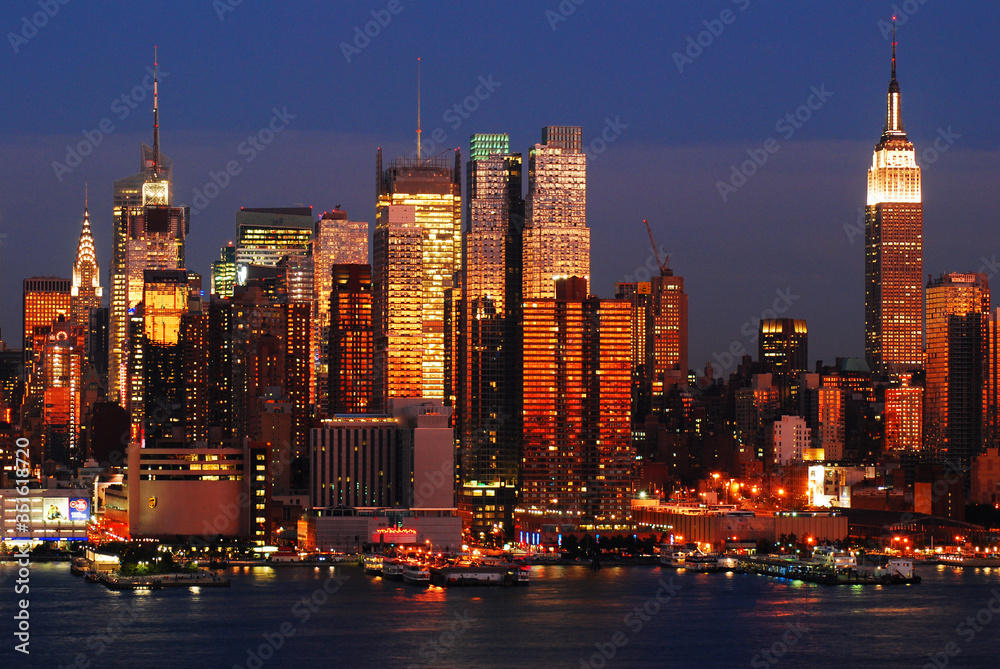 The sunset colors are reflected in the glass skyscrapers of Manhattan