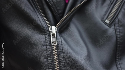 Close up woman hand zips leather jacket. 