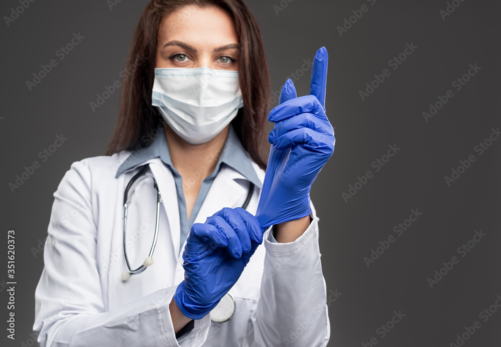 Female doctor putting on latex gloves Female doctor putting on latex gloves