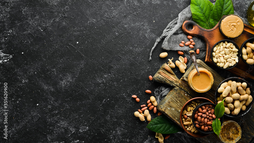 Peanut butter and nuts on a black stone background. Healthy food. Top view.