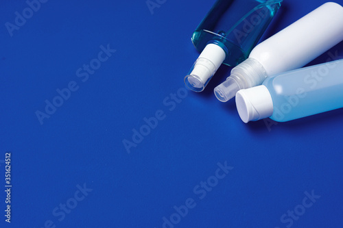 Bottles with antibacterial hand sanitizer on blue background with copy space