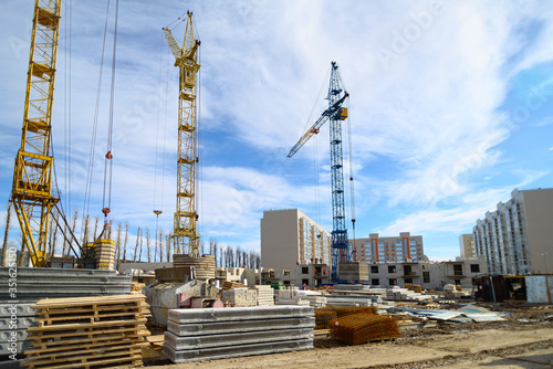 Photos of high-rise construction cranes and an unfinished house against a blue sky. Photographed on a wide angle lens.