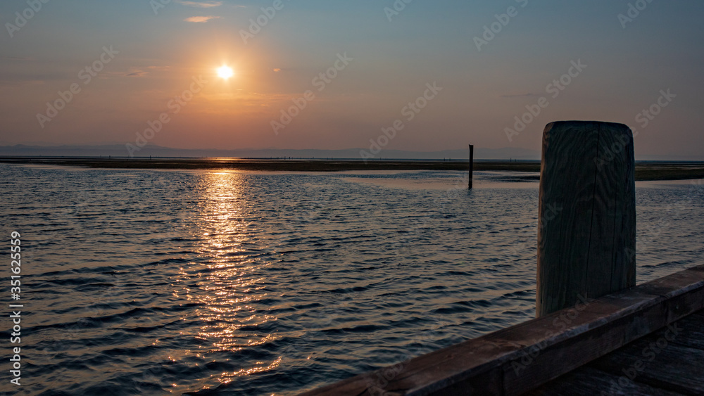 Scenic view of sunrise at the sea, view with wooden post. Beautiful sunrise in Grado Pineta, Italy.