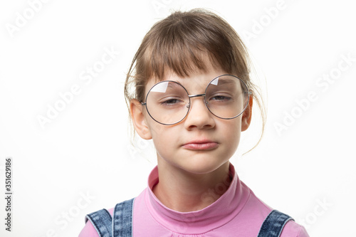 Portrait of a funny girl in glasses squinting eyes on a white background