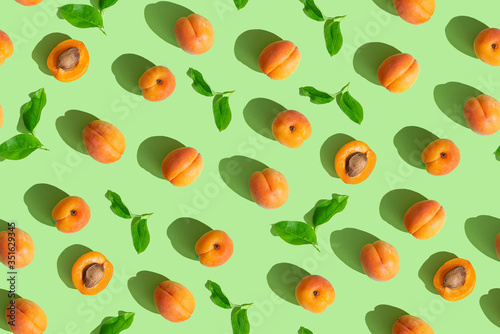 Apricot seamless pattern. Trendy summer background. Ripe fresh apricots on green background. Top view, flat lay. Summer sale, advertizing, Wrapping paper, poster, greeting card, cover background.