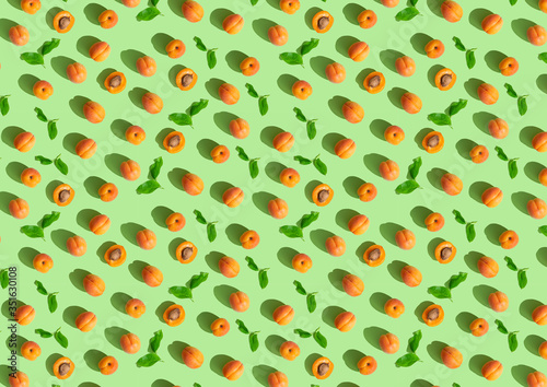 Apricot seamless pattern. Trendy summer background. Ripe fresh apricots on green background. Top view, flat lay. Summer sale, advertizing, Wrapping paper, poster, greeting card, cover, fabric design.