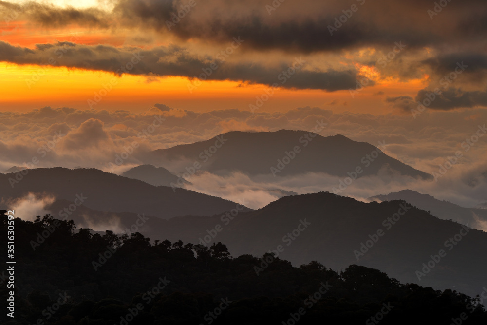 Naklejka premium Costa Rica sunset landscape. Hills of Tapantí nationl park cloud forest, Costa Rica. Tropical mountains with white storm clouds. Rainy day in the forest. Tropic landscape in Cetral America, sunset.