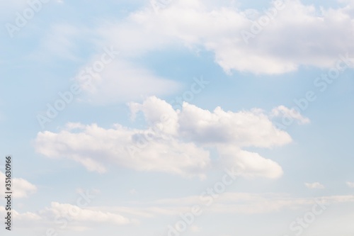 Light blue sky with delicate fluffy clouds