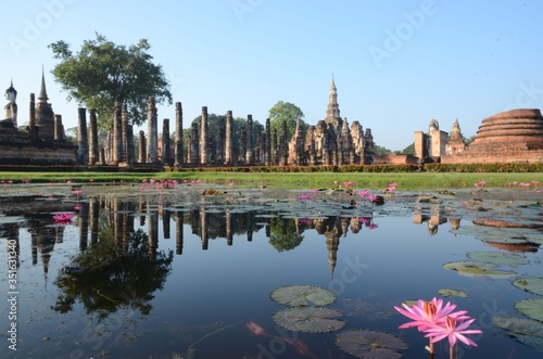 The amazing Wat Mahathat in the Historical Park of Sukhothai is reflecting in the clear lake full of lotus flowers