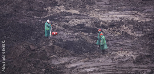 Workers in the mud of a construction site at the stage of excavation; construction of a supermarket AUCHAN