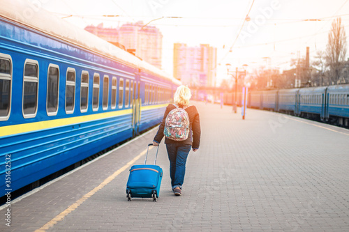 Fototapeta Naklejka Na Ścianę i Meble -  Woman traveler tourist walking with luggage at train station, copy space