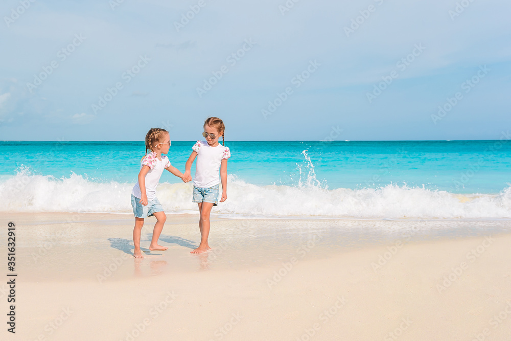 Adorable little girls have a lot of fun on the beach.