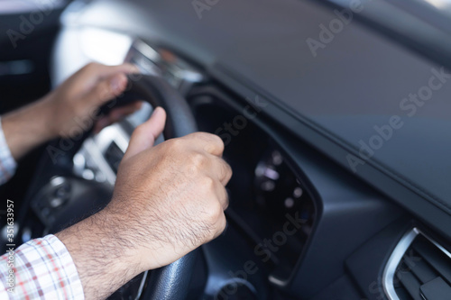 Close up of hand hold steering wheel young man driver a car riding on the road. trip of travel. vehicle transportation and safe driving concept.