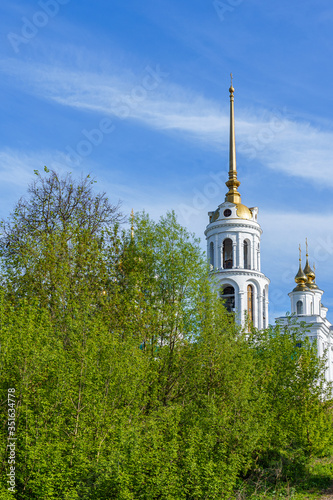 Obraz na płótnie domes of an orthodox temple made of golden metal and the steeple of a bell tower against a blue sky w salonie