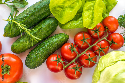 cherry tomatoes on a branch and cucumbers, cabbage, lettuce, rosemary, tomato, dill, different types of vegetables top view.