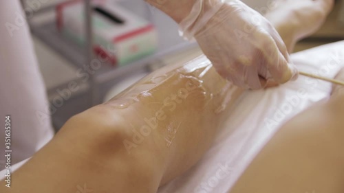 Wallpaper Mural laser hair removal of slender legs of a girl. Beautician smears a transparent gel on the skin of a girl Torontodigital.ca