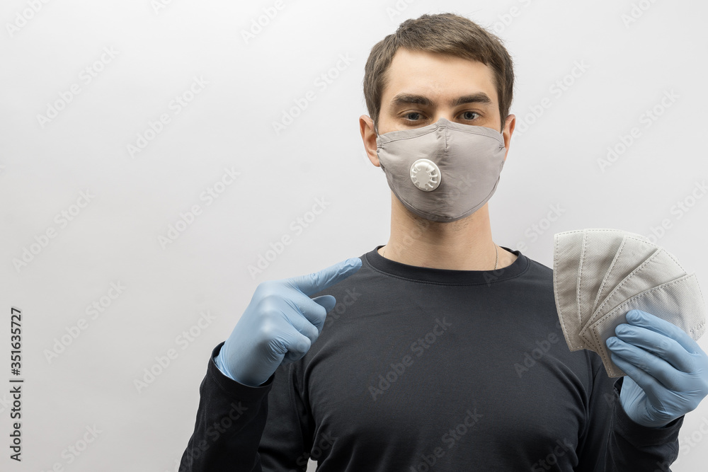 Young european man wearing mask against the corona virus and thumbs up covid 19 man wearing reusable surgical mask to prevent from virus white\grey background Corona virus pandemic funny fun Young european man wearing mask against the corona virus and thumbs up covid 19 man wearing reusable surgical mask to prevent from virus white\grey background Corona virus pandemic funny fun