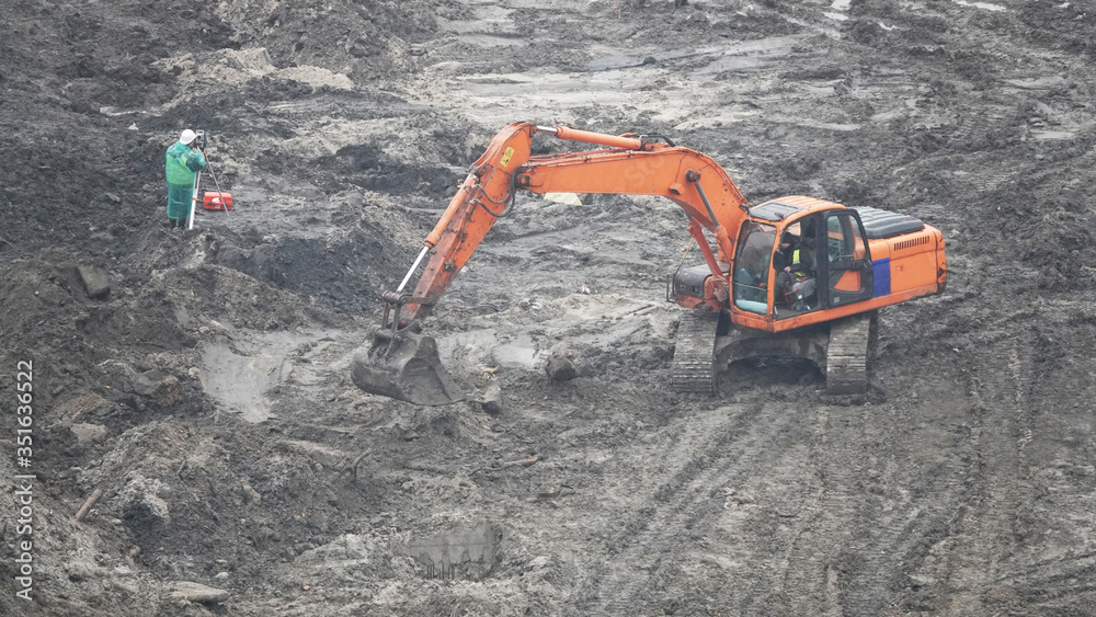Workers in the mud of a construction site at the stage of excavation; construction of a supermarket AUCHAN Workers in the mud of a construction site at the stage of excavation; construction of a supermarket AUCHAN