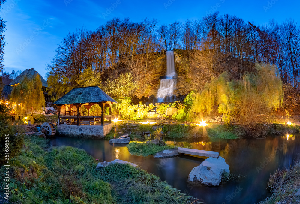 Obraz premium Night scene of Maramures with traditional maze mill among the river and a small waterfall in Sighetu Marmatiei