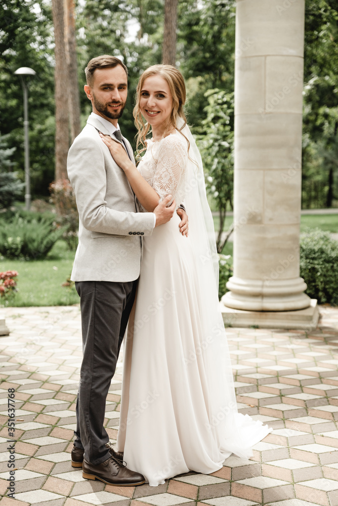 Naklejka premium touch of the bridegroom on the wedding day,wedding couple meeting in the park,joyful couple,laughing groom with a beard looks at a joyful bride