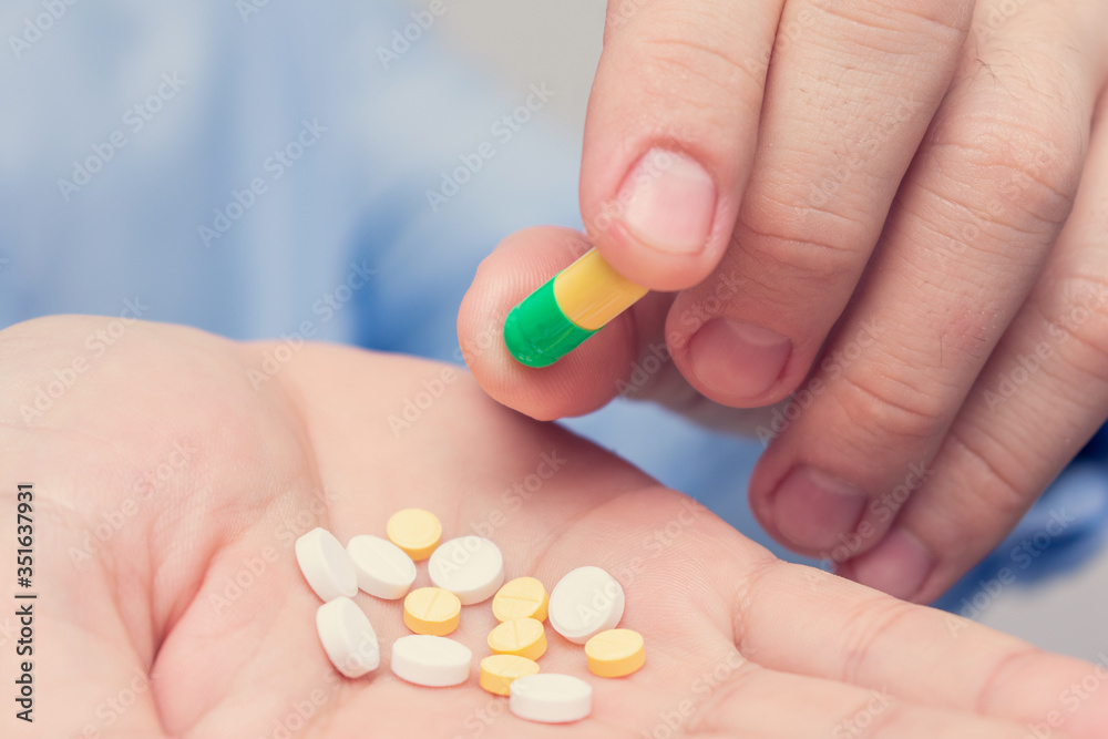 Pills in hand, man's hand and capsules, closeup, cropped image Pills in hand, man's hand and capsules, closeup, cropped image