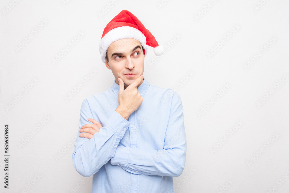 Concept of a new year. Thoughtful man in Santa Claus hat, portrait, white background Concept of a new year. Thoughtful man in Santa Claus hat, portrait, white background