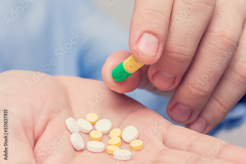 Pills in hand, man's hand and capsules, closeup, cropped image