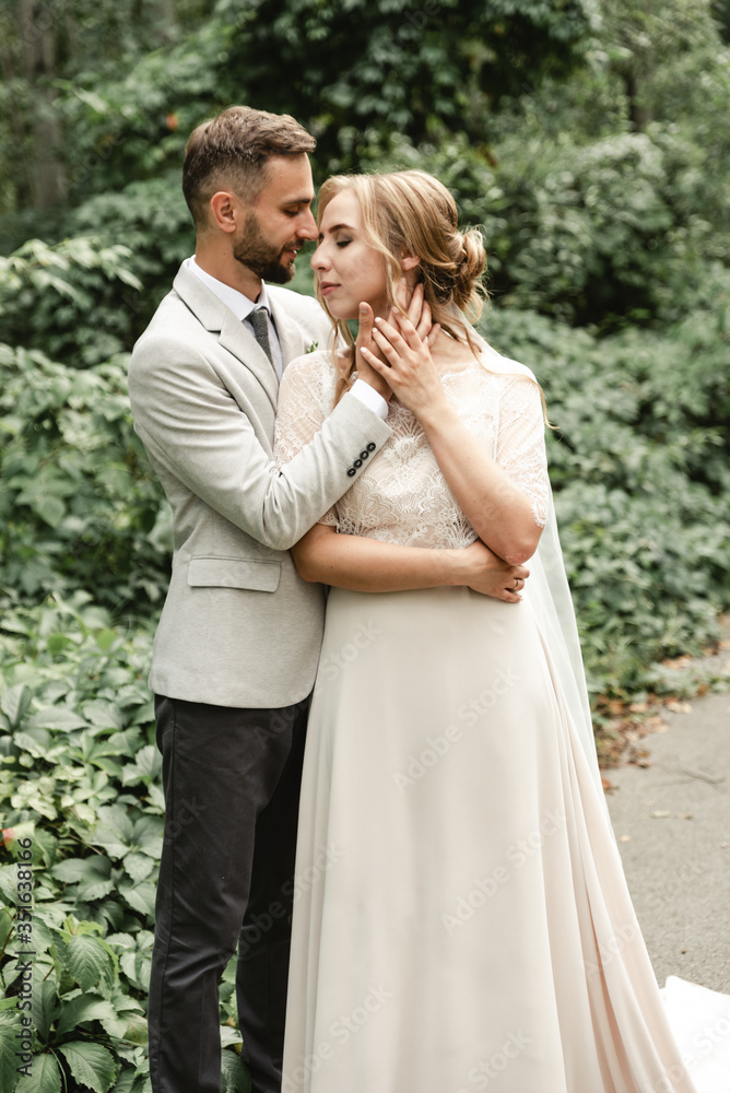 holiday newlyweds,tender hugs of a young couple,the groom touches the face of the bride,cheerful and joyful wedding couple walks in the park