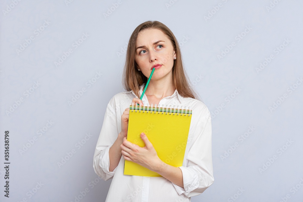 Brooding student girl solves a difficult task, gray background, copy space Brooding student girl solves a difficult task, gray background, copy space