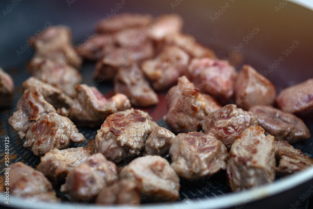 Close up of meat beef cubes chunks in a frying pan. Preparing dinner concept