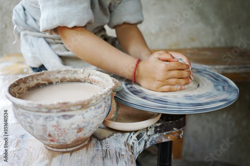 
little student makes a ceramic cup on a potter's wheel in a master class photo