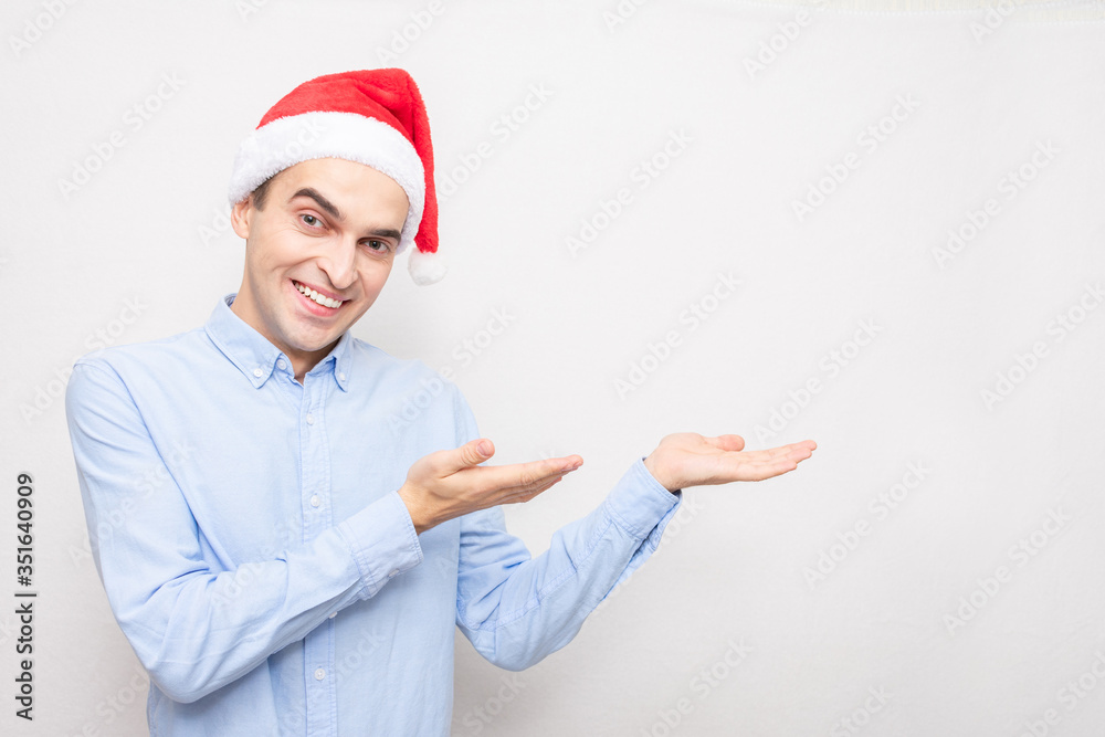 Joyful man in the Santa Claus hat shows empty space, copy space