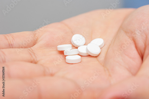 White pills in hand  a man s hand and a handful drugs  close-up  cropped image