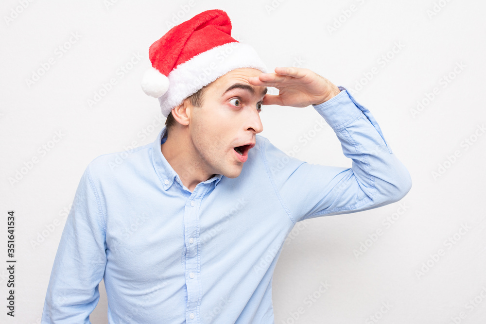 Stunned shocked guy in the hat of Santa Claus look away, portrait, white background Stunned shocked guy in the hat of Santa Claus look away, portrait, white background