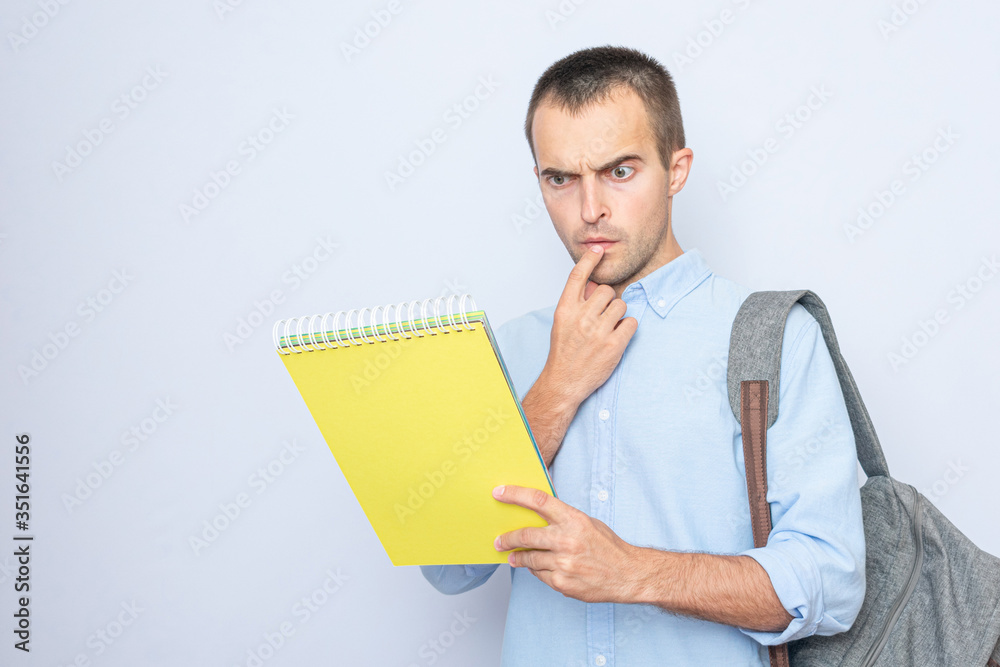 Serious student guy with red book, gray background Serious student guy with red book, gray background