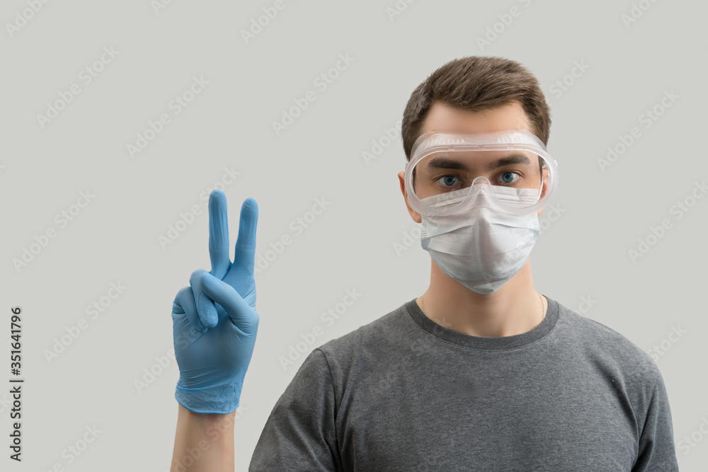 Young european man wearing reusable mask against the corona virus covid 19  man wearing surgical mask to prevent from virus white\grey background Corona virus pandemic