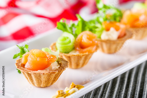 delicious snack tartlets on rustic wooden background