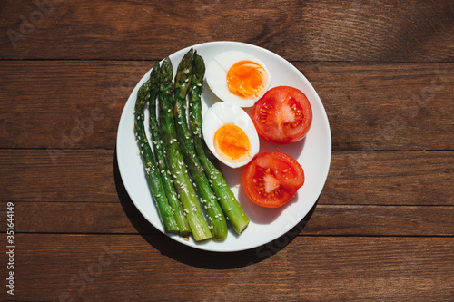 Breakfast with asparagus, egg and tomatoes. Vegetables. Food on wooden background.