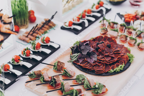 Delicious appetizer and canape on table at wedding reception in restaurant. Luxury catering service. Italian delicatessen, prosciutto snacks, cheese and olives. Christmas feast