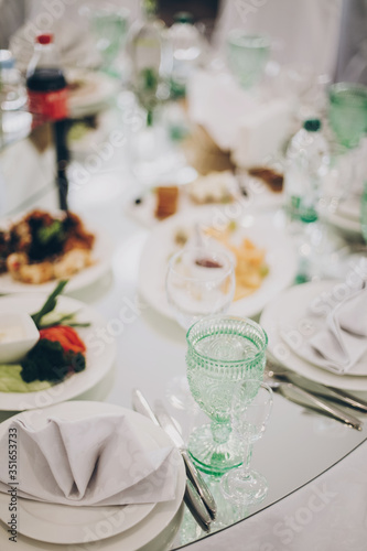Wedding luxury table setting at reception in restaurant. Stylish glasses for wine, plate with napkin, cutlery and food on tables. Luxury catering service. Christmas feast
