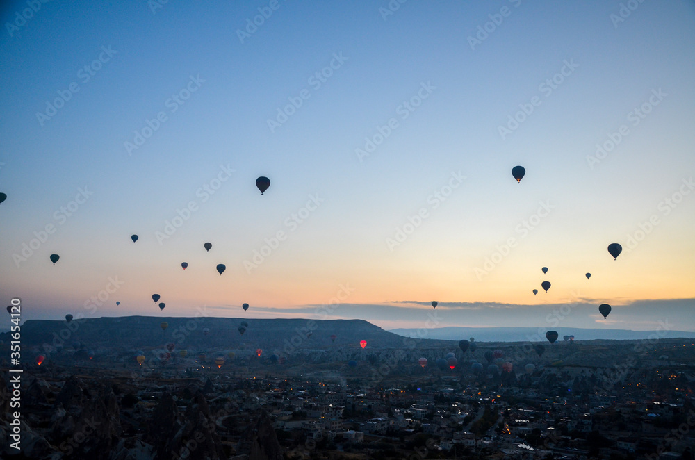 Hot air balloons at sunrise flying in the sky along valleys at Cappadocia of Goreme, Turkey 