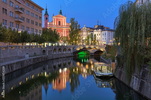 Ljubljana, Slovenia. Evening view on Franciscan Church of the Annunciation and Triple Bridge across the Ljubljanica River. Latin motto on the facade of the church reads: Hail, full of grace!