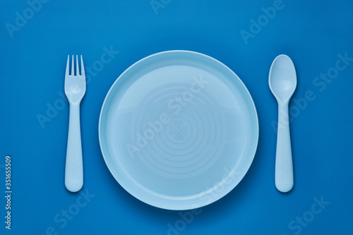 Plastic blue cutlery set with blue background. Top view