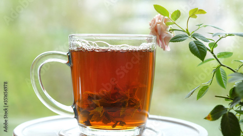 Pouring the tea with leaves of currant, lemon balm, mint, raspberry in a glass cup.Tea party outdoors