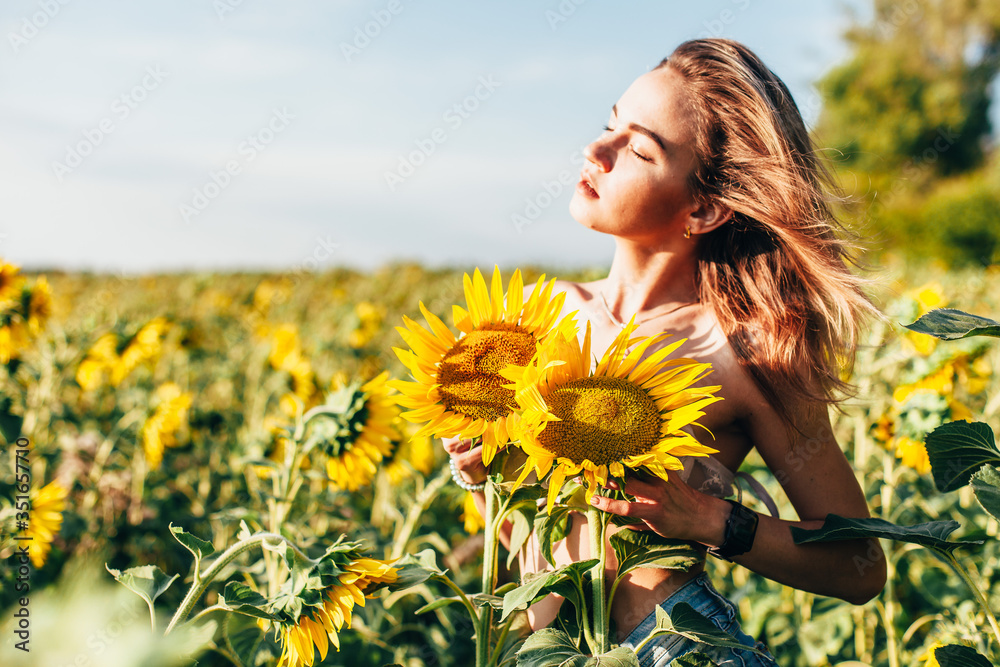 A young topless girl stands in sunflowers A young topless girl stands in sunflowers