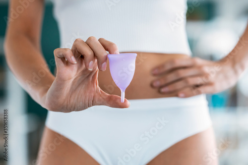 Young woman hands holding menstrual cup on the bathroom. photo