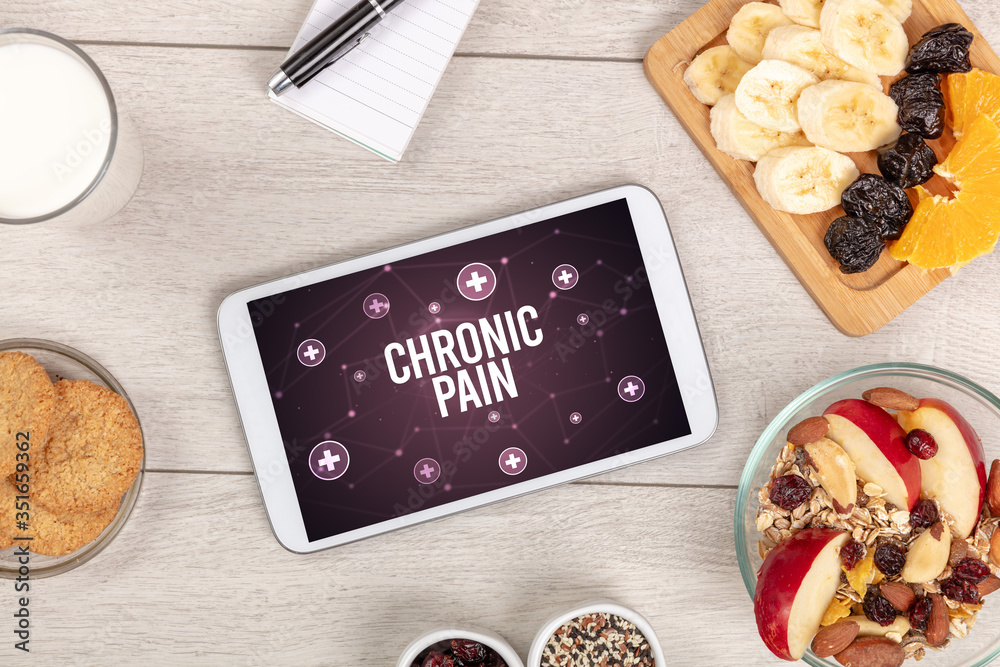 CHRONIC PAIN concept in tablet pc with healthy food around, top view CHRONIC PAIN concept in tablet pc with healthy food around, top view